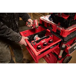 A person using a Divider for PACKOUT Drawer Tool Boxes to organize a red tool drawer with power tools and batteries.