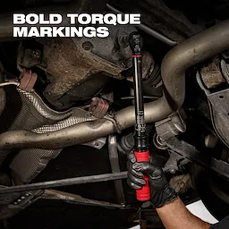 3/8” Drive Click Torque Wrench (20-100 ft·lbf) held by a gloved hand, tightening a bolt under a vehicle with bold torque markings visible.