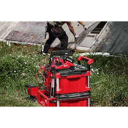 M18 TOP-OFF 350W Power Supply & Charger w/ PACKOUT Compatibility stacked on red tool boxes outdoors.