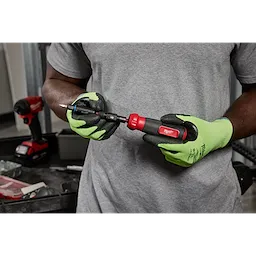 A person holds the Milwaukee 8-IN-1 Multi-Bit & Nut Driver W/ SHOCKWAVE Impact Duty Bits & Nut Drivers in their hands. The tool has a red handle and interchangeable bits, designed for impact duty applications.