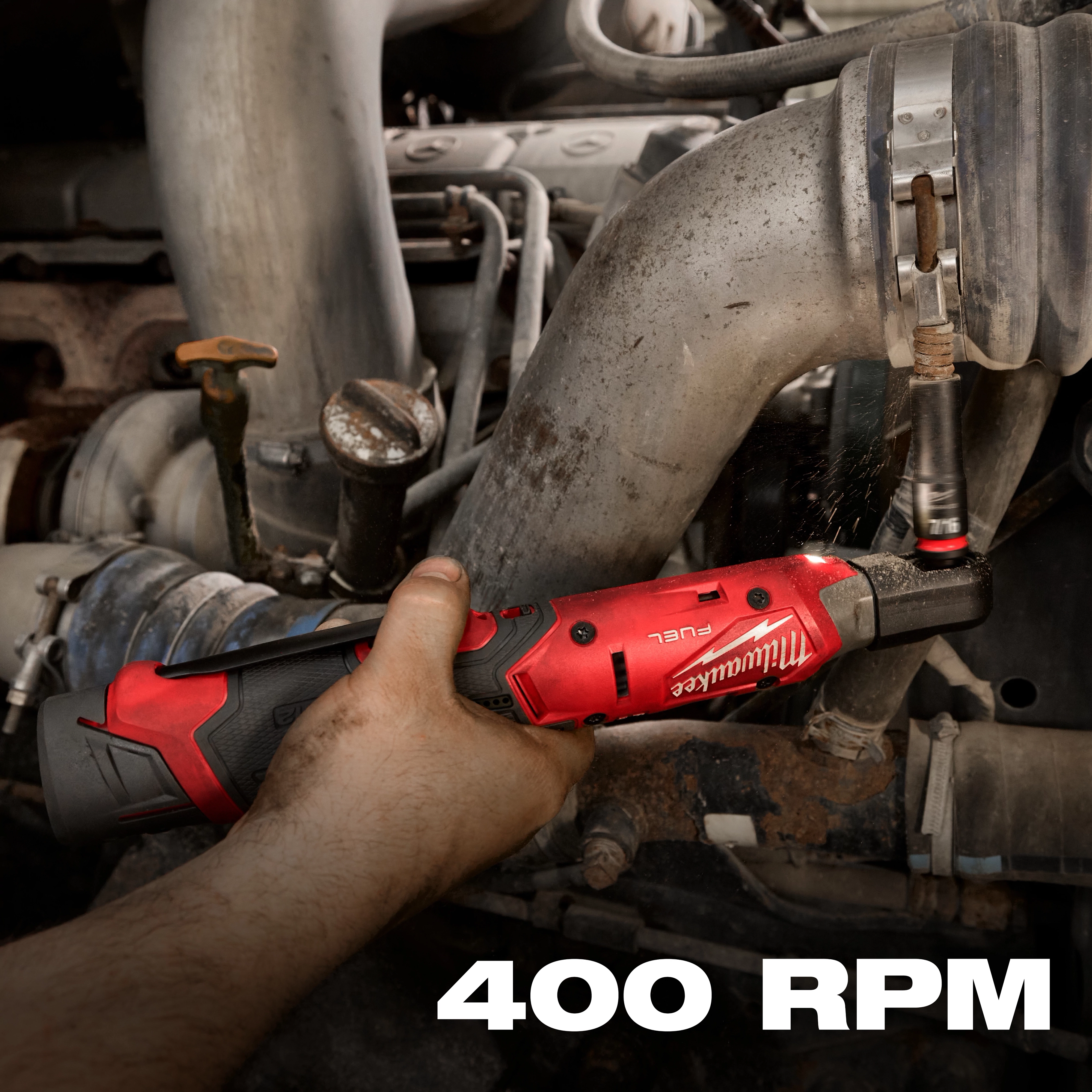 A person uses the M12 FUEL™ 3/8" Ratchet on a metallic pipe in an automotive setting. The tool, red and black in color, is shown in action, and the text "400 RPM" is displayed at the bottom.