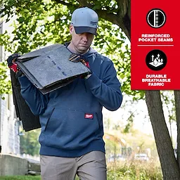 Person carrying panels outdoors while wearing a blue FREEFLEX Pullover Hoodie with work gloves and cap.