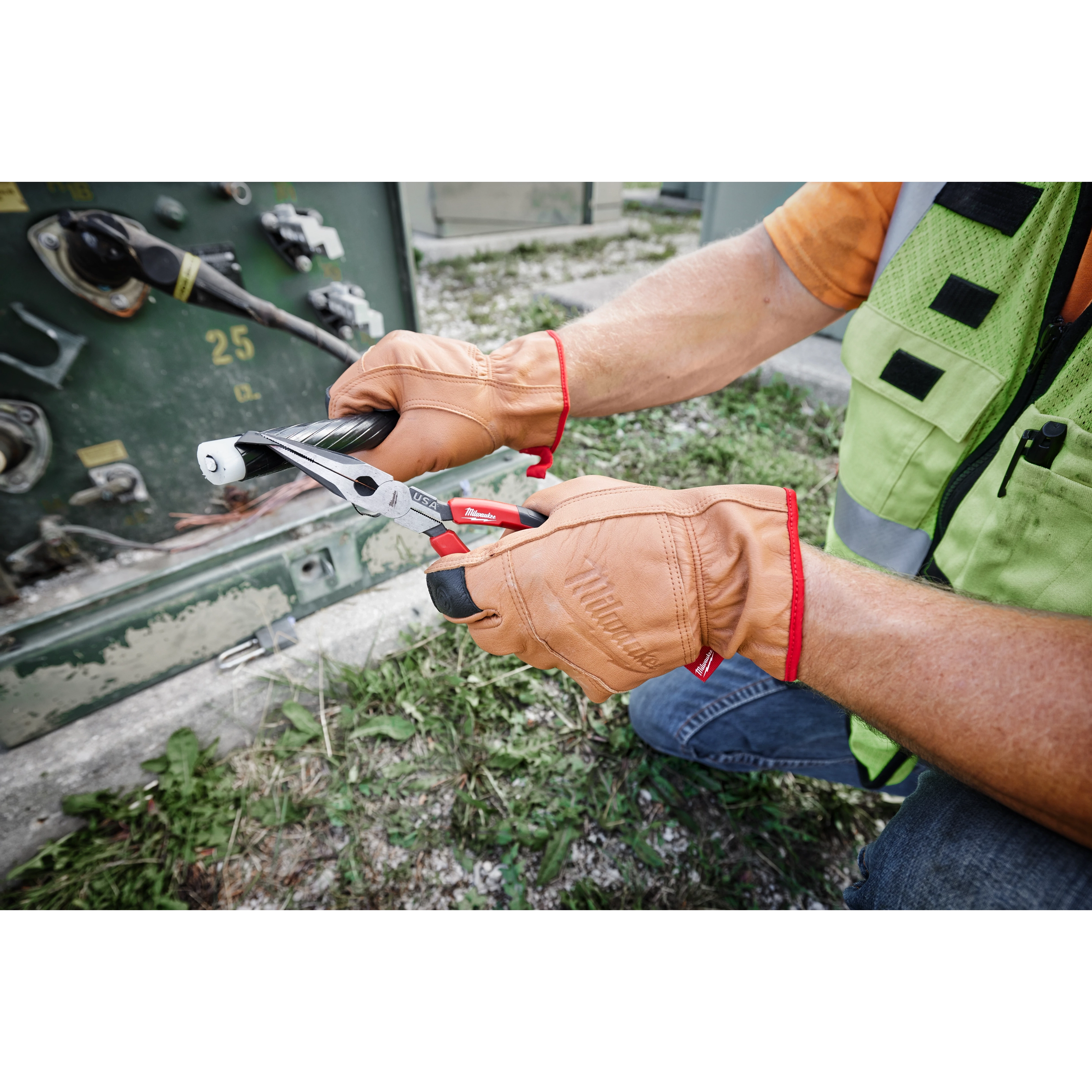 Person wearing Goatskin Leather Gloves - XL while using pliers to work with electrical cables outdoors.