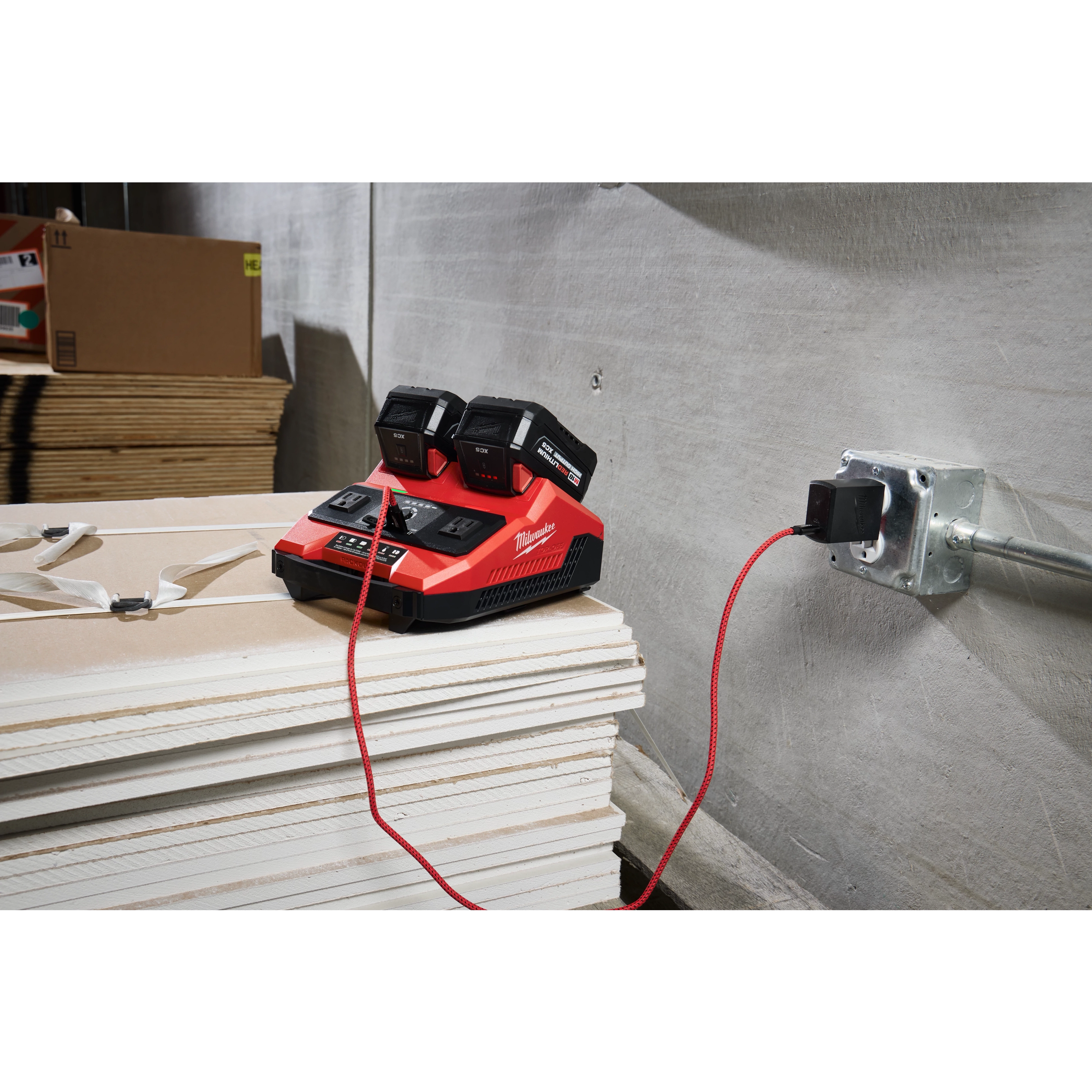 M18 TOP-OFF 350W Power Supply & Charger w/ PACKOUT Compatibility on stacked boards, plugged into a wall outlet.