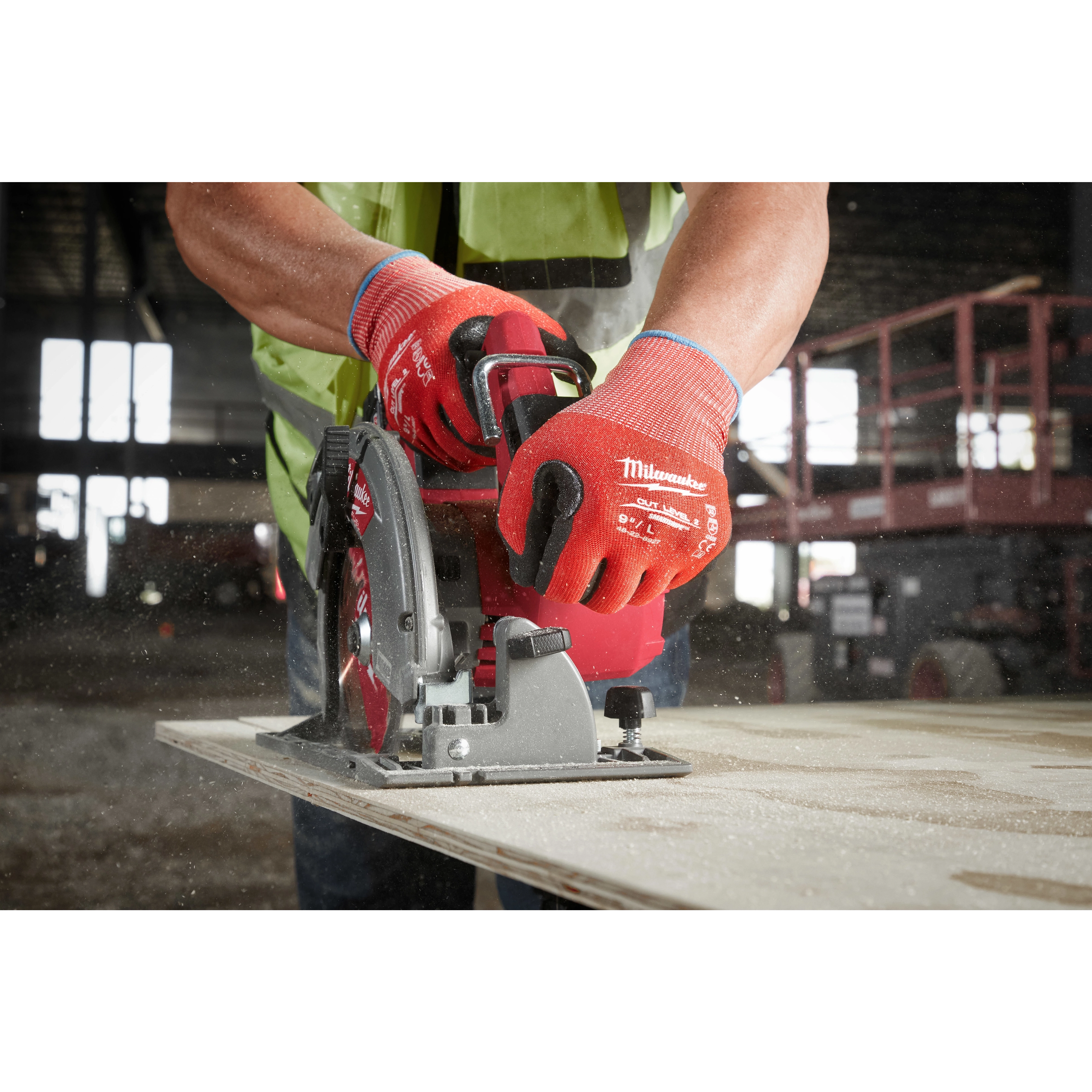 Person wearing Cut Level 2 Nitrile Dipped Gloves - L operating a circular saw to cut a piece of wood in a workshop.
