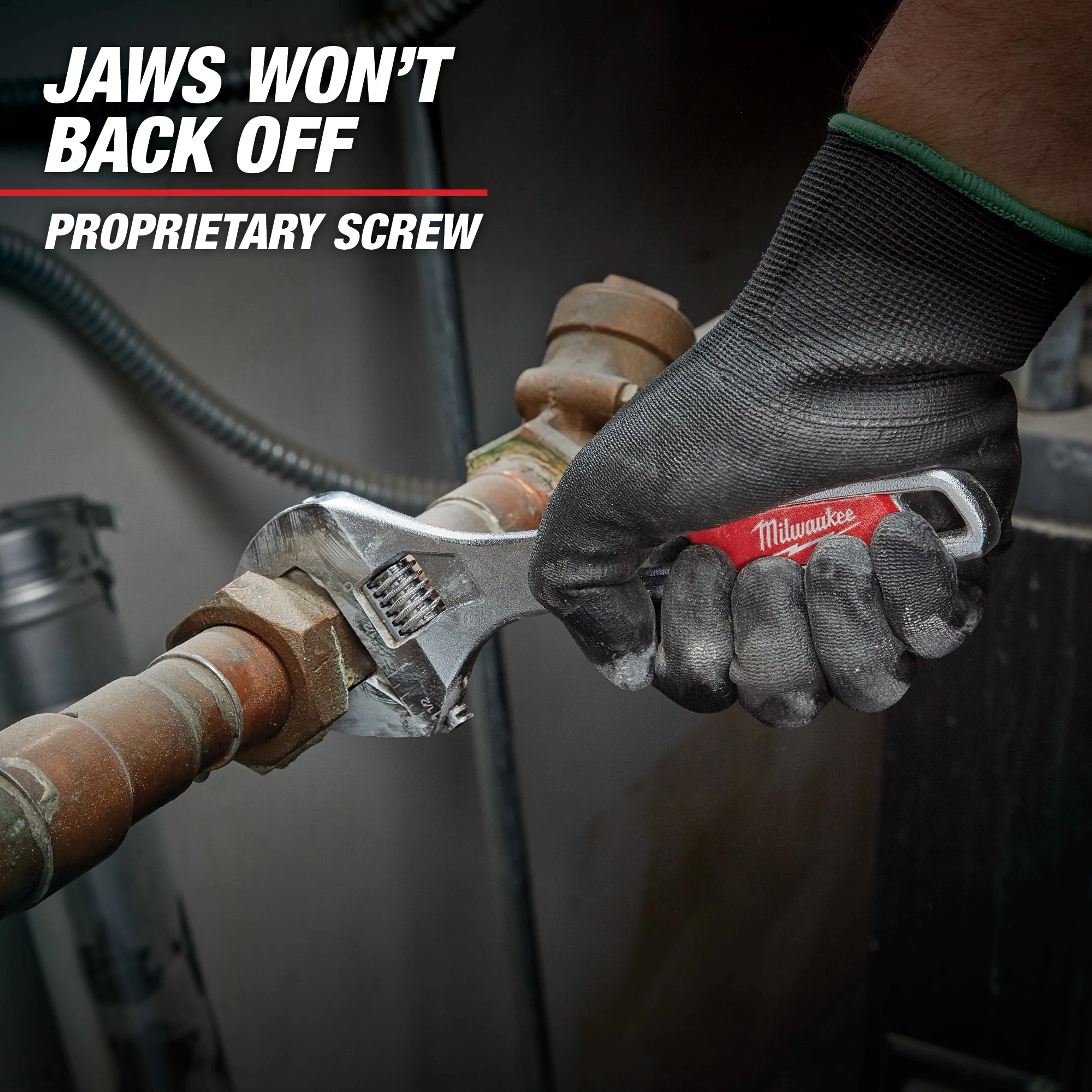 A gloved hand holds a Milwaukee adjustable wrench, tightening a brass pipe fitting. Text on the image reads "Jaws won't back off. Proprietary screw." The wrench has a red handle and is being used in a mechanical or plumbing setting.