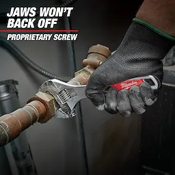 A gloved hand holds a Milwaukee adjustable wrench, tightening a brass pipe fitting. Text on the image reads "Jaws won't back off. Proprietary screw." The wrench has a red handle and is being used in a mechanical or plumbing setting.