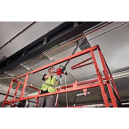 Worker on an elevated platform using an M18 FUEL 1K Wire Puller to pull cable overhead.