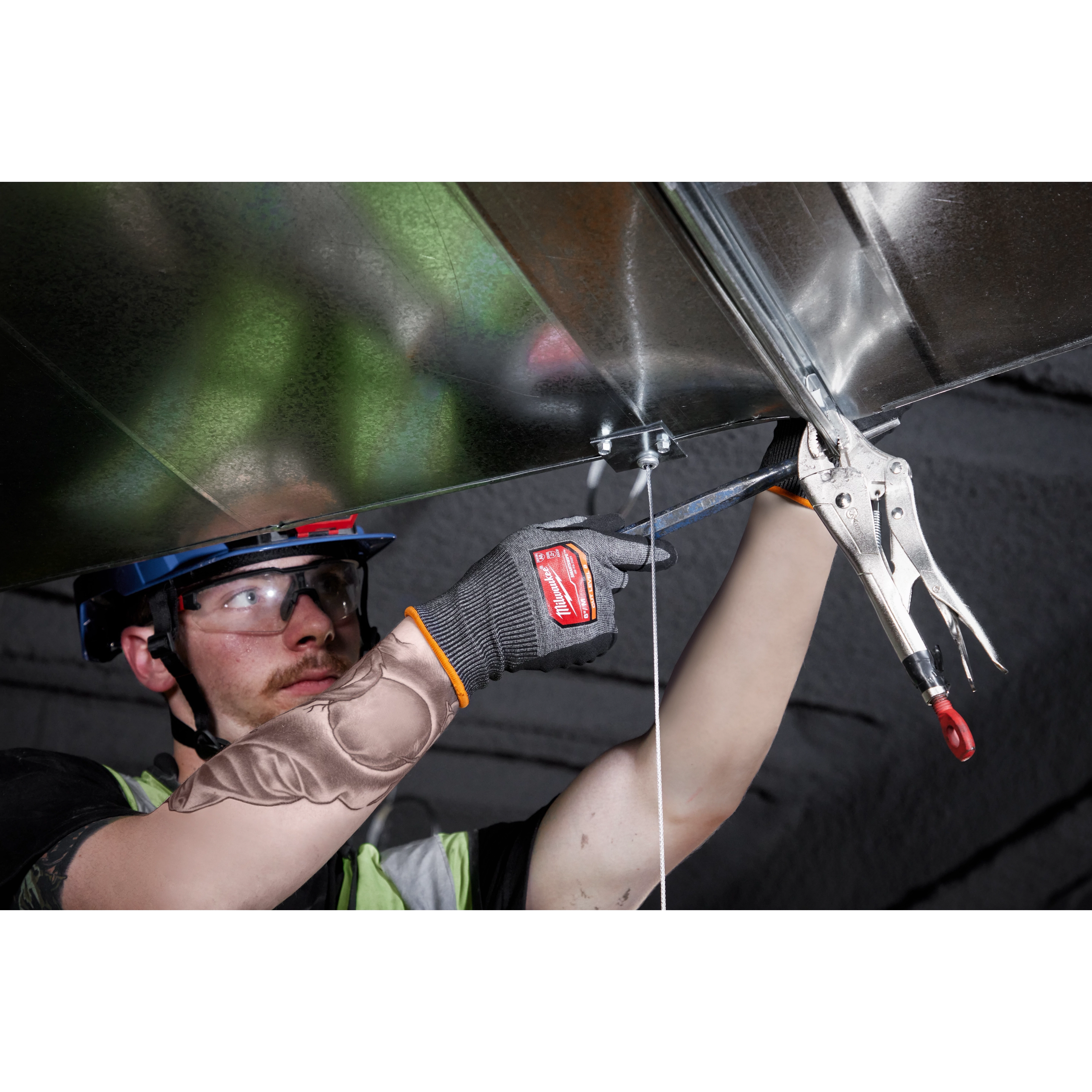 Person wearing Cut Level 8 High-Dexterity Nitrile Dipped Gloves - L while using a clamp tool to hold a metal sheet overhead.