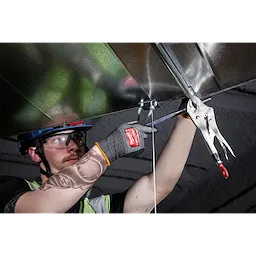 Person wearing Cut Level 8 High-Dexterity Nitrile Dipped Gloves - L while using a clamp tool to hold a metal sheet overhead.