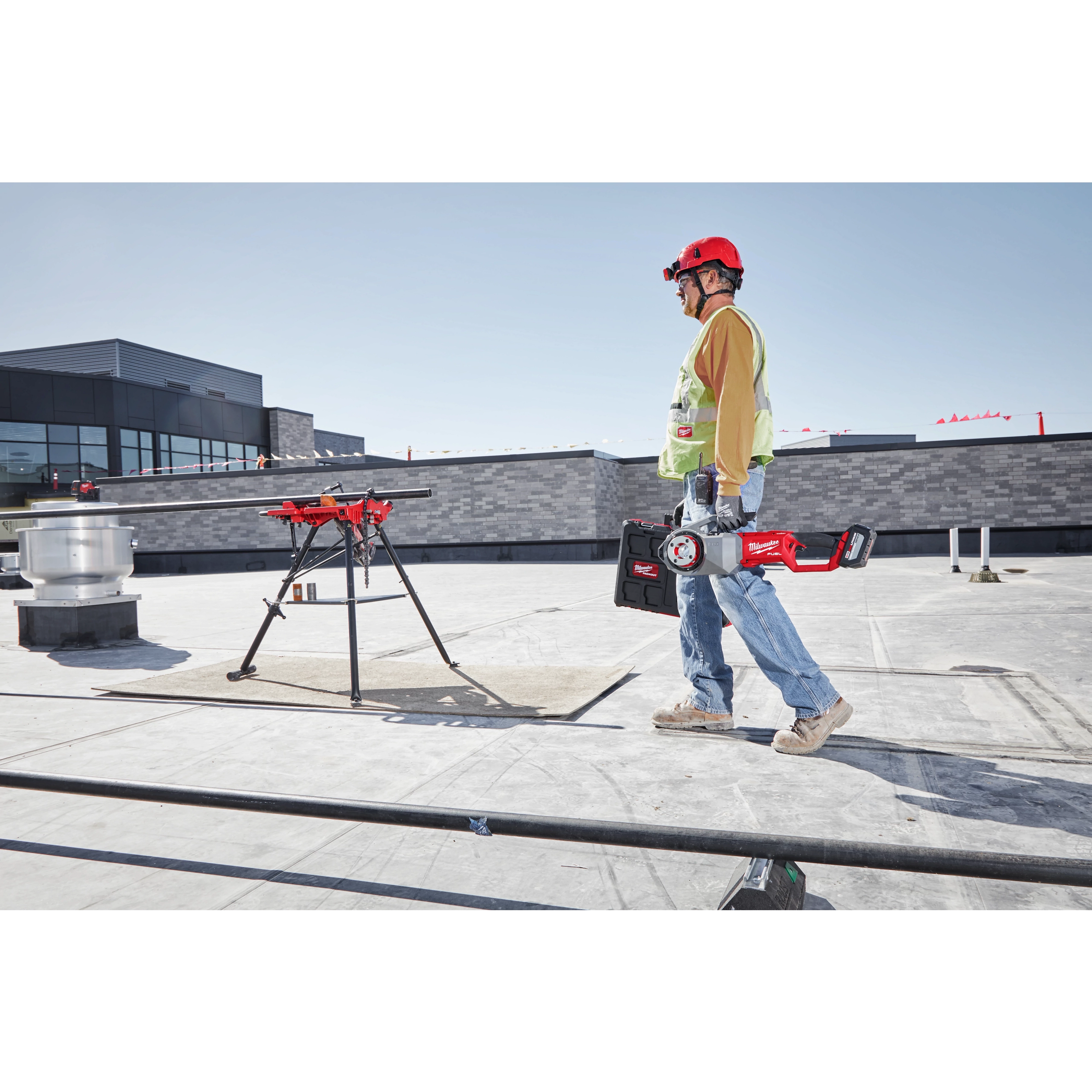 Worker carrying the M18 FUEL Pipe Threader on the jobsite