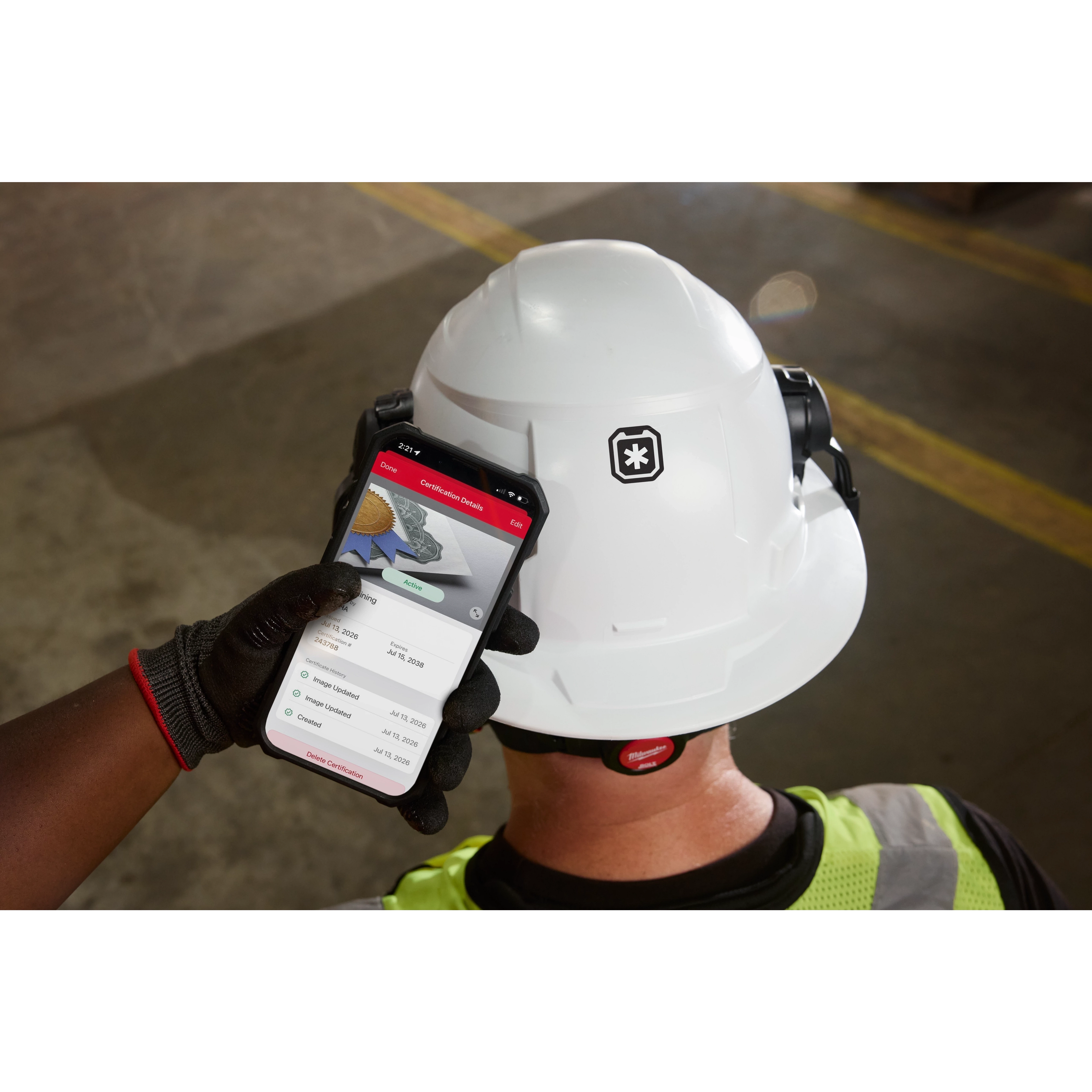 Worker wearing a hard hat with BOLT™ ID w/ ONE-KEY™ viewed on a smartphone screen held beside the helmet.