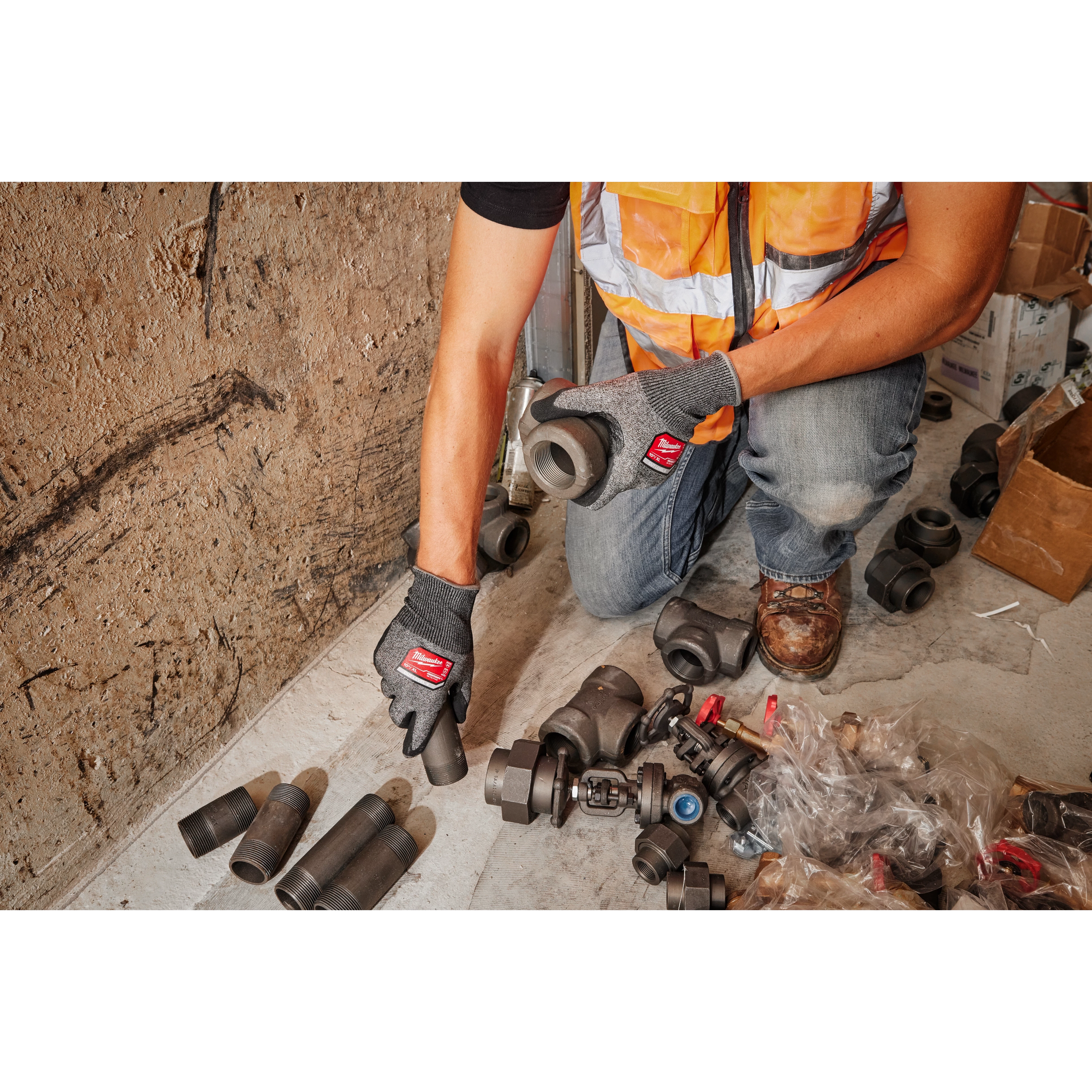 Technician wearing Cut Level 4 High-Dexterity Nitrile Dipped Gloves - XL handles pipes and fittings in a workshop setting.