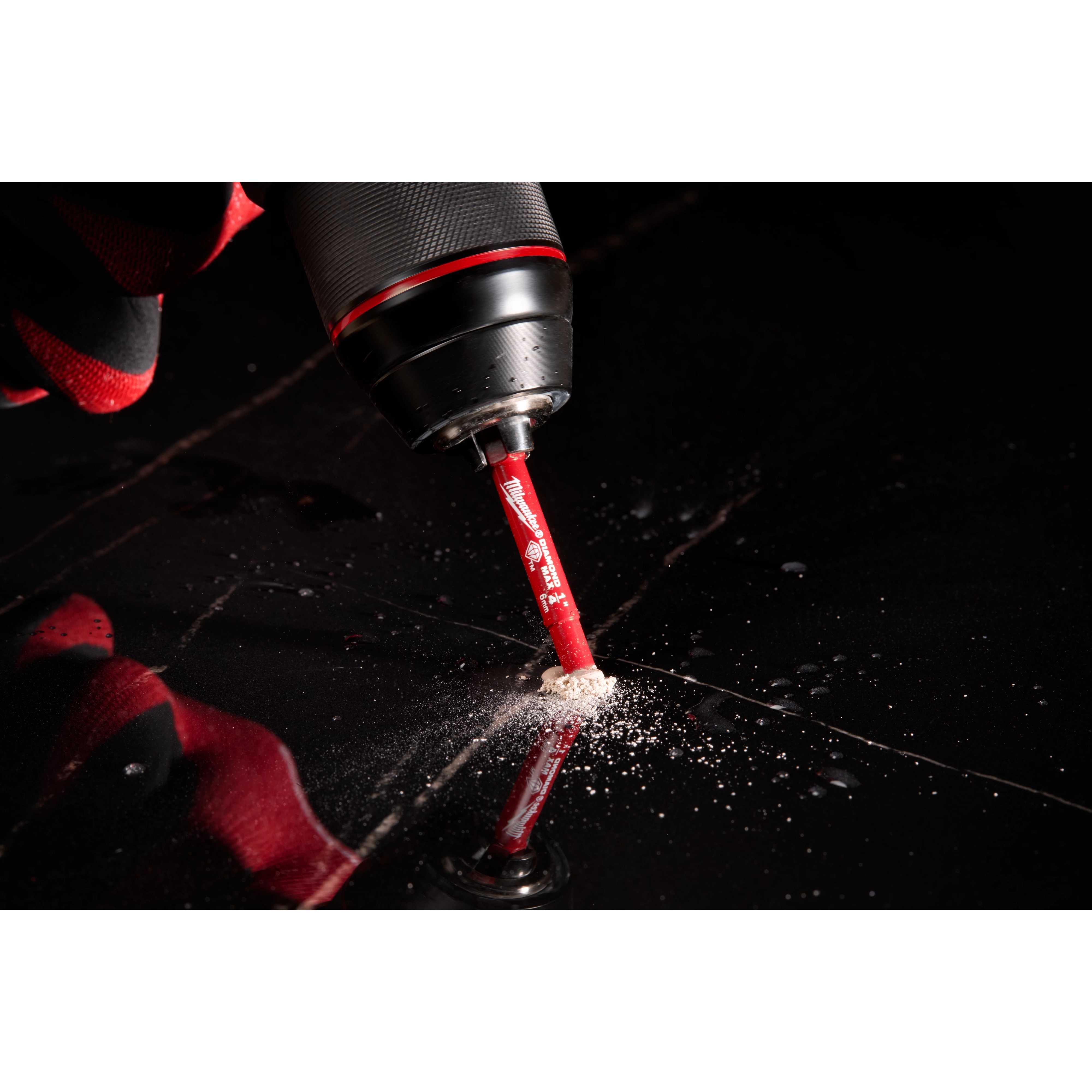 A Milwaukee® 1/4" DIAMOND MAX™ Hole Saw Bit is attached to a power drill, cutting through a dark material. Dust and debris can be seen around the drilling site. The bit is red with white text and branding.