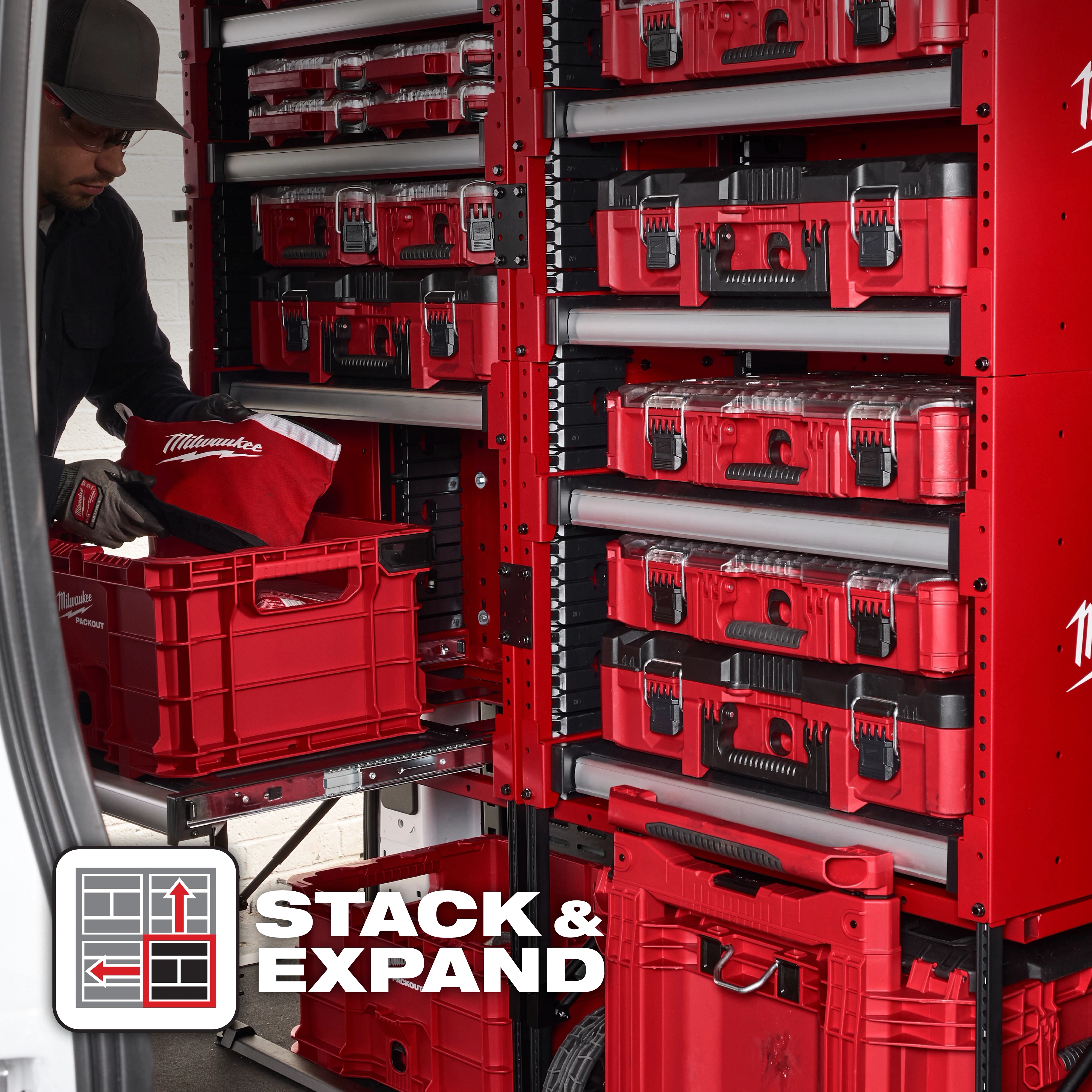 PACKOUT™ Rack product image showcasing red stackable toolboxes and bins on organized metal shelving. A person is handling a red bin with a Milwaukee item inside. The "STACK & EXPAND" icon is displayed in the bottom left corner, highlighting the modularity feature of the storage system.
