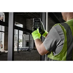Person wearing High Visibility Cut Level 1 Polyurethane Dipped Glove - L, operating a smartphone on a construction site.