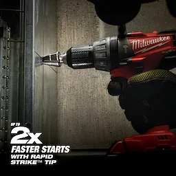 A red and black cordless drill is being used by a gloved hand to bore through a metal wall, showcasing Jam Free Step Bits. Text indicates the product offers "up to 2x faster starts with Rapid Strike tip." The drill and bits are positioned horizontally against the wall during operation.