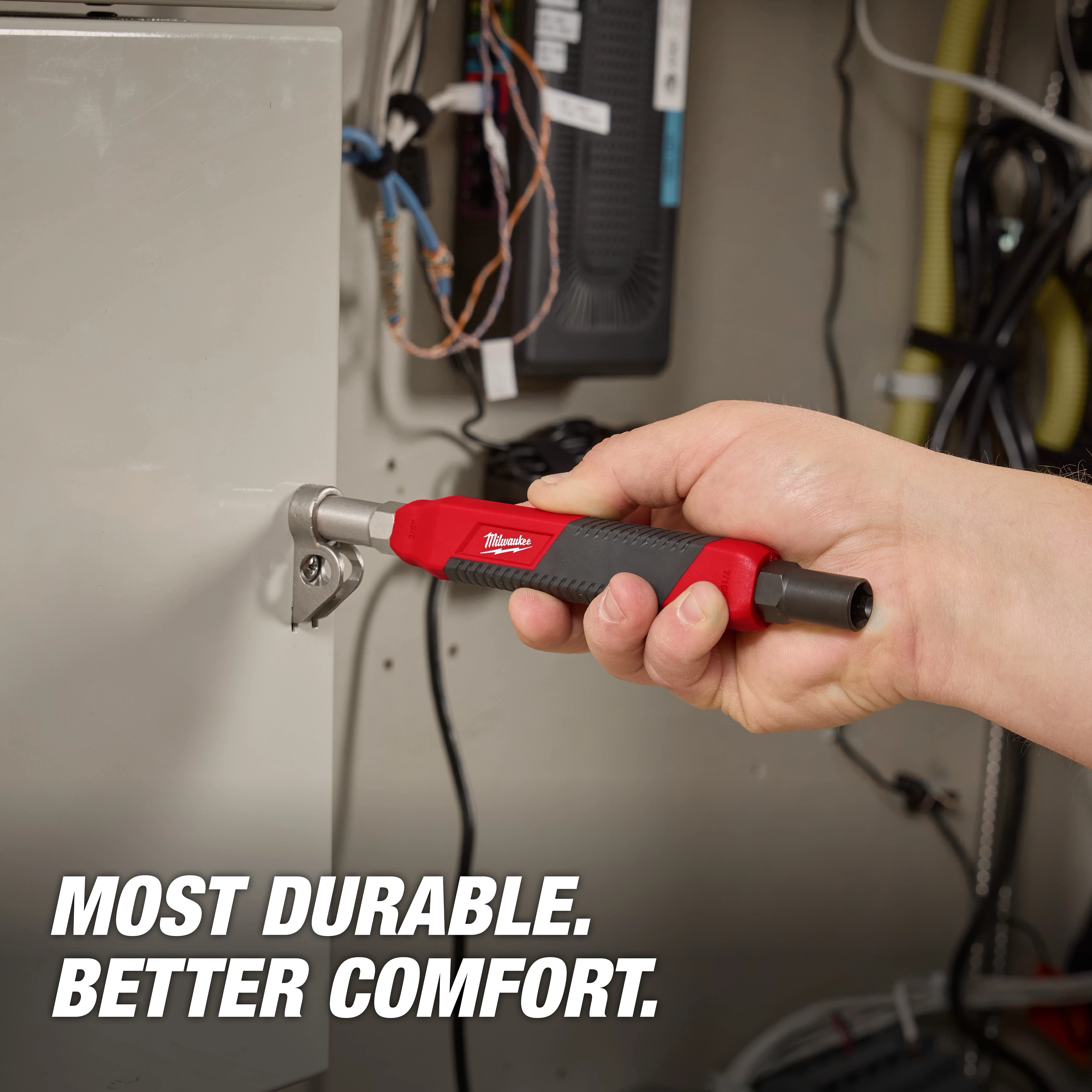 A hand uses a Can Wrench (3/8” & 7/16”) to turn a lock on an electrical panel. The wrench has a red and black handle with "Milwaukee" branding. Text reads, "Most durable. Better comfort."