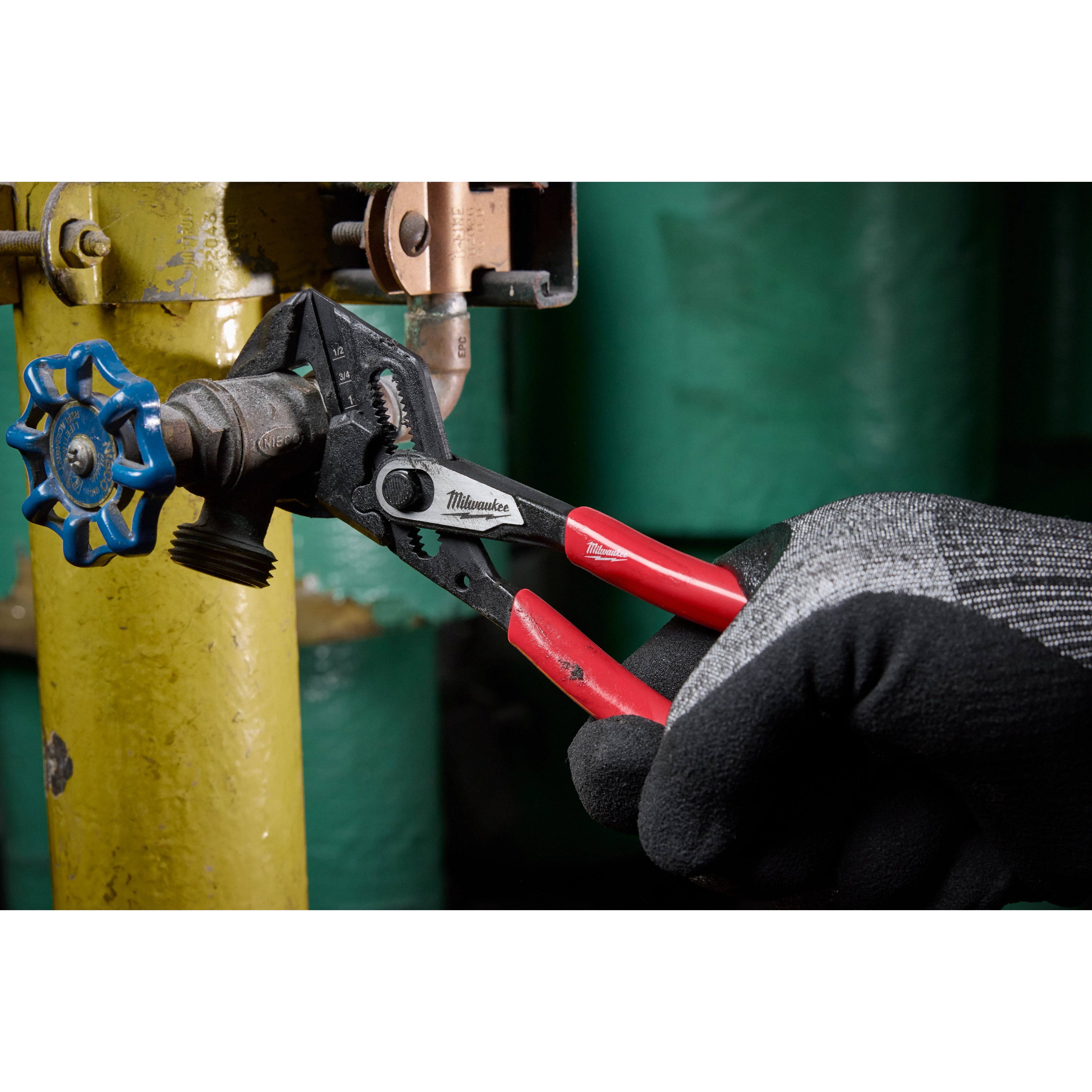 A gloved hand is using a 7" Pliers Wrench with black and red handles to turn a valve attached to a yellow pipe.