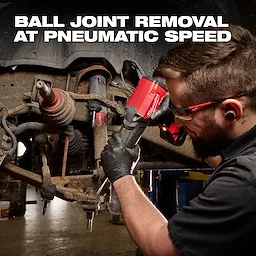 Mechanic using the red M18 FUEL STRIKER Hammer Chisel on a vehicle suspension assembly.