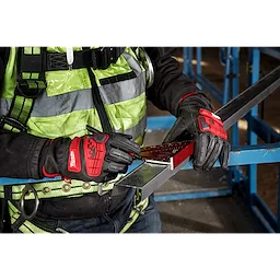 Person wearing Impact Cut Level 5 Goatskin Leather Gloves holding a metal sheet and measuring tool at a construction site.