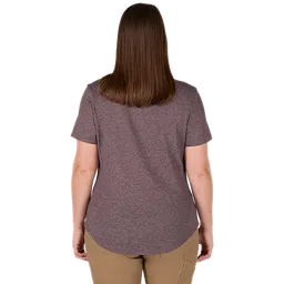 A woman is standing facing away, wearing the Women's FREEFLEX™ Hybrid Tee - Short Sleeve in purple. The shirt has a rounded hem and is paired with beige pants. Her brown hair is straight and reaches her shoulders.