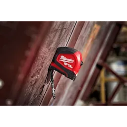 10ft/3m Keychain Tape Measure with LED in red and black, hanging from a wall with a keychain attached.