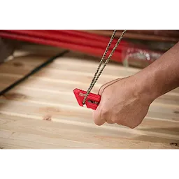 A hand using the Multi-function Compact Utility Knife to cut a piece of rope on a wooden surface. The small, red utility knife is held firmly, demonstrating its capability to slice through durable material efficiently.